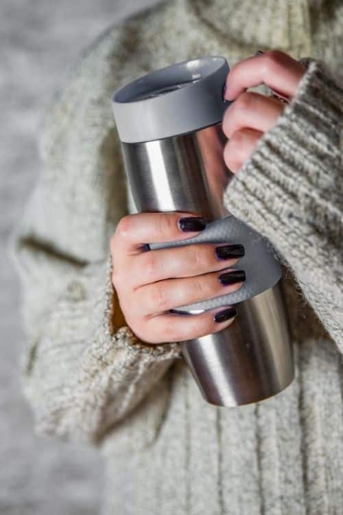 Girl holding travel tumbler and wearing sweater, cant see face