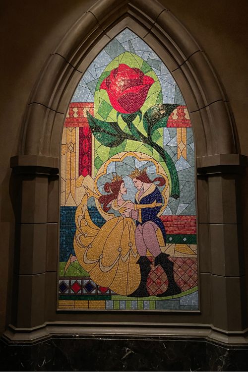 inside beast's castle a glass art window of belle and beast and the enchanted rose