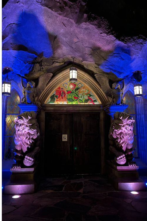 beast's castle at night front door entrance with two lion statues on side, doors closed