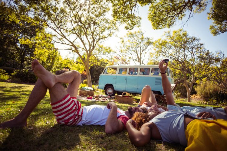 old school van in background, adults laying on floor after a picnic