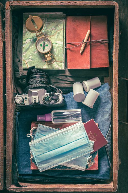 packed camera, fae mask, sanitizer,  compass, map, pencil, and red travel journal. jeans underneath