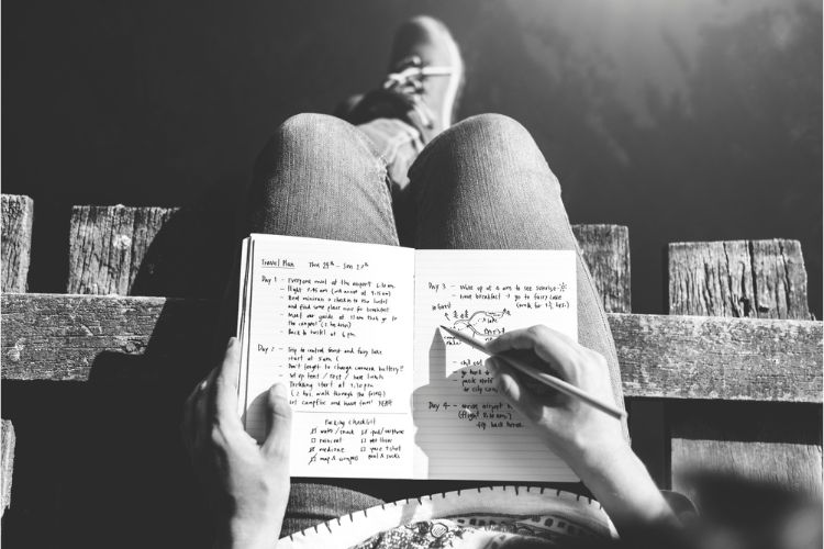 girl sitting on ledge writing in notebook 