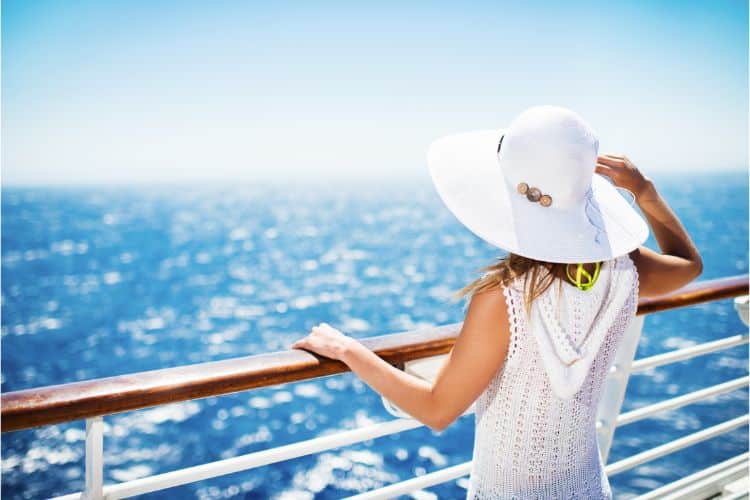 Disney cruise packing list: Bring a sunhat like this girl whos looking over the sea and wearing a white sunhat and white cover-up