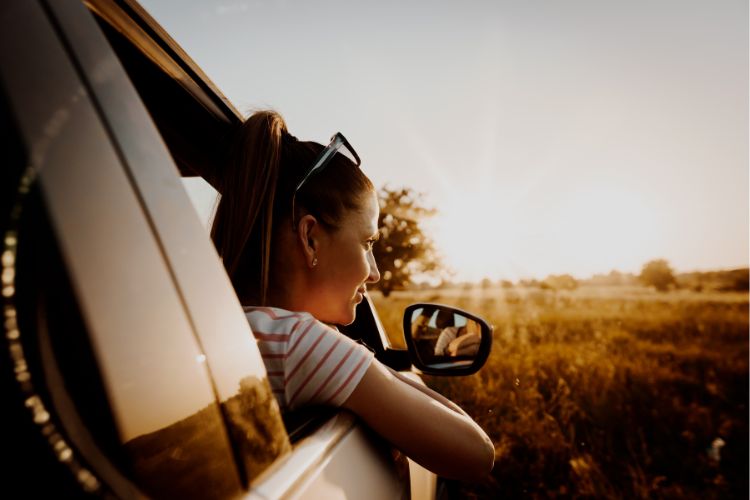 woman looking out car window during road trip pit stop