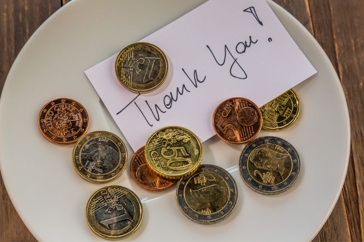 coins left in dish with thank you note, a common way for tipping in italy